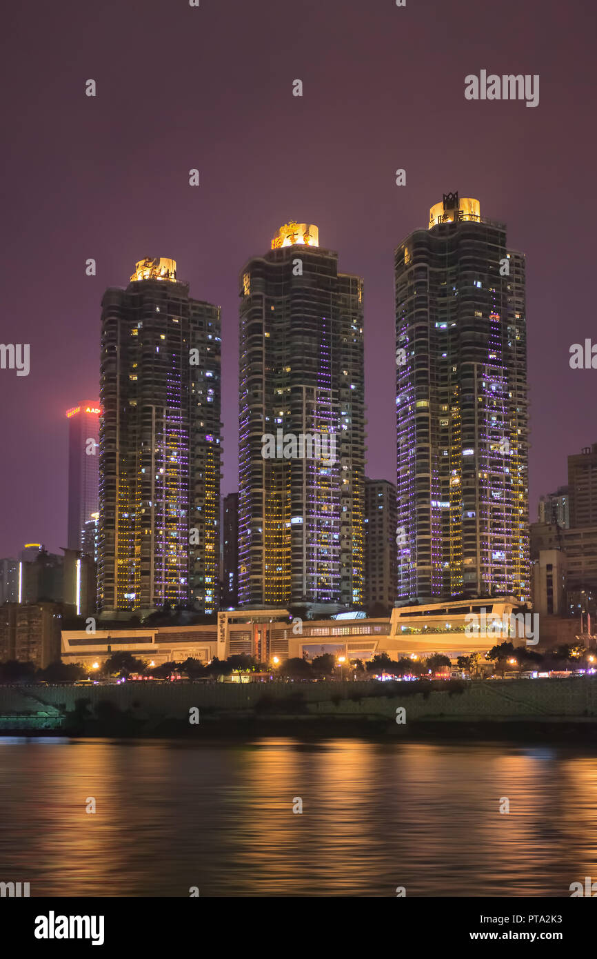 Illuminated modern apartment buildings at night near a river in Chongqing, China. Stock Photo