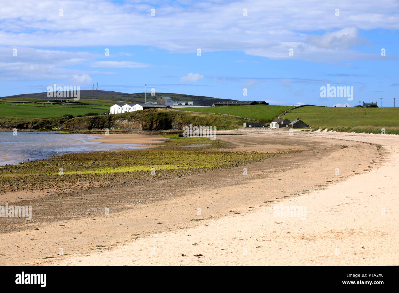 Scapa Bay near Kirkwall in Orkney with the Scapa distillery buildings sitting above the shoreline in the distance, Orkney, Scotland, Highlands, United Stock Photo