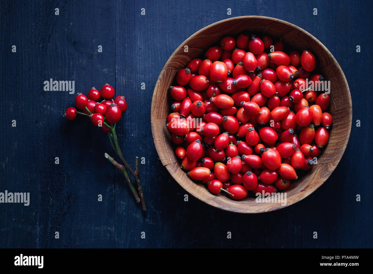 Freshly picked rose hips. Wooden bowl of rose hip or rosehip, commonly known as the dog rose (Rosa canina). Stock Photo