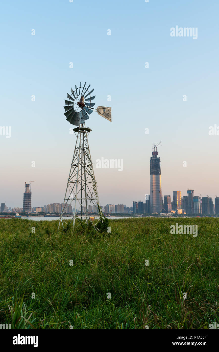 Multi-bladed windpump in middle of Hankou marshland and Wuhan city skyline in background in Hubei China Stock Photo