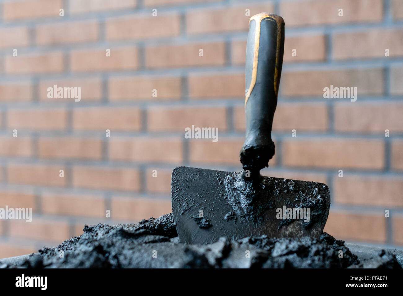 Bricklayers trowel in fresh mortar with bricks wall n the background