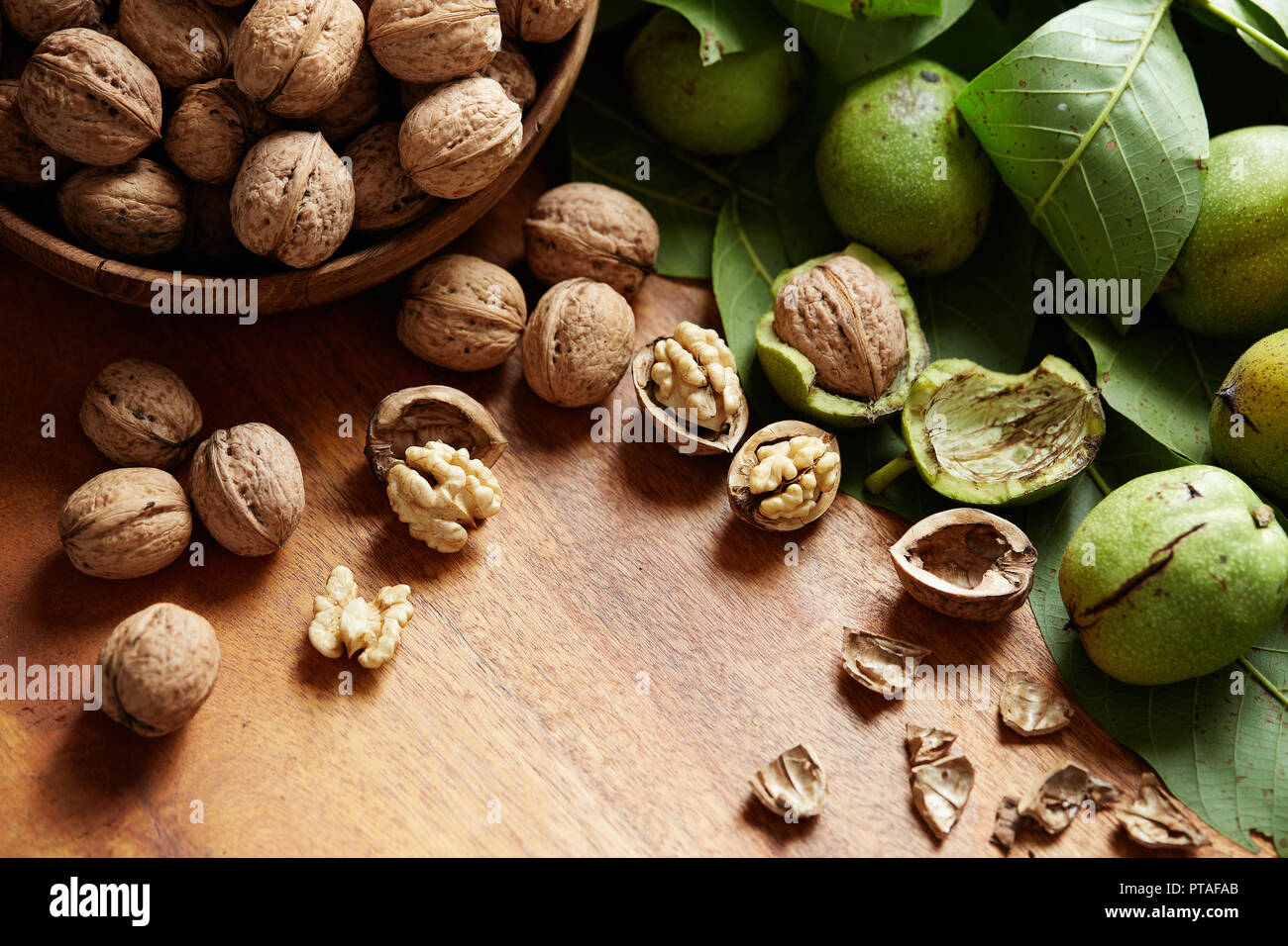 Fresh walnuts with and without shells on a wooden surface. Walnuts, shelled and unshelled. Stock Photo