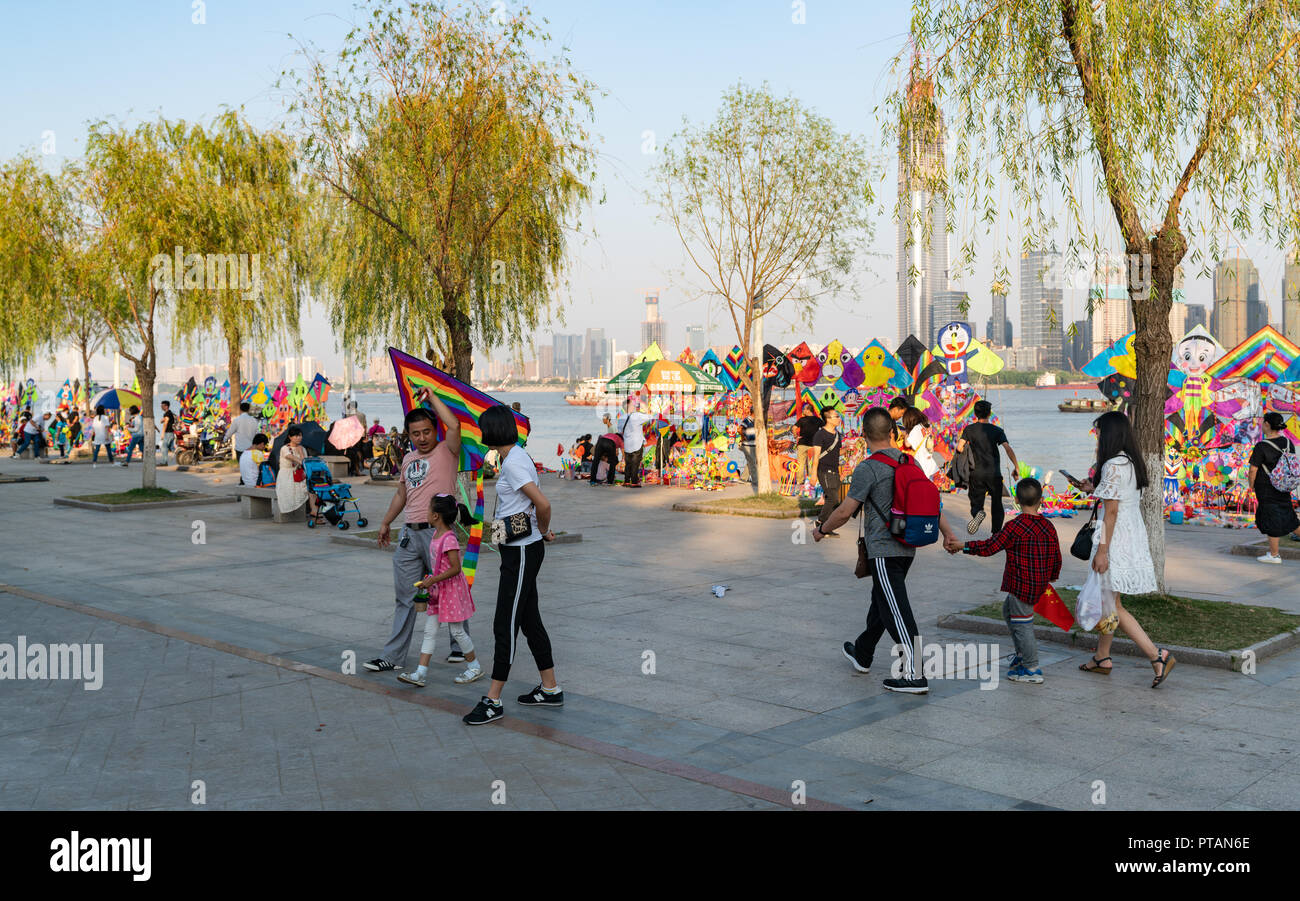 4 October 2018, Wuhan China : Chinese family holding a kite and kite stalls on yangtze riverside park in background Wuhan Hubei China Stock Photo