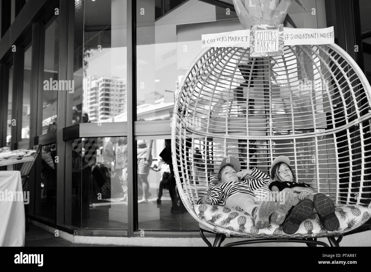 Children sitting and lounging in a big pineapple chair, Cotters market on Flinders Street, central business district of Townsville City QLD, Australia Stock Photo