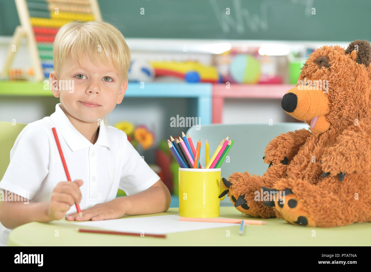 Cute little boy drawing with pencils in classroom Stock Photo - Alamy