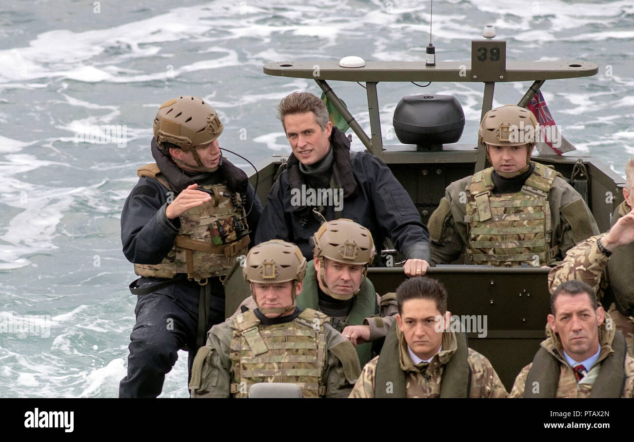 Defence Secretary Gavin Williamson, (back row second left) watches as Royal Marines commandos perform a raid on a ship during a visit to HMS Montrose at HMNB Devonport, Plymouth. Stock Photo