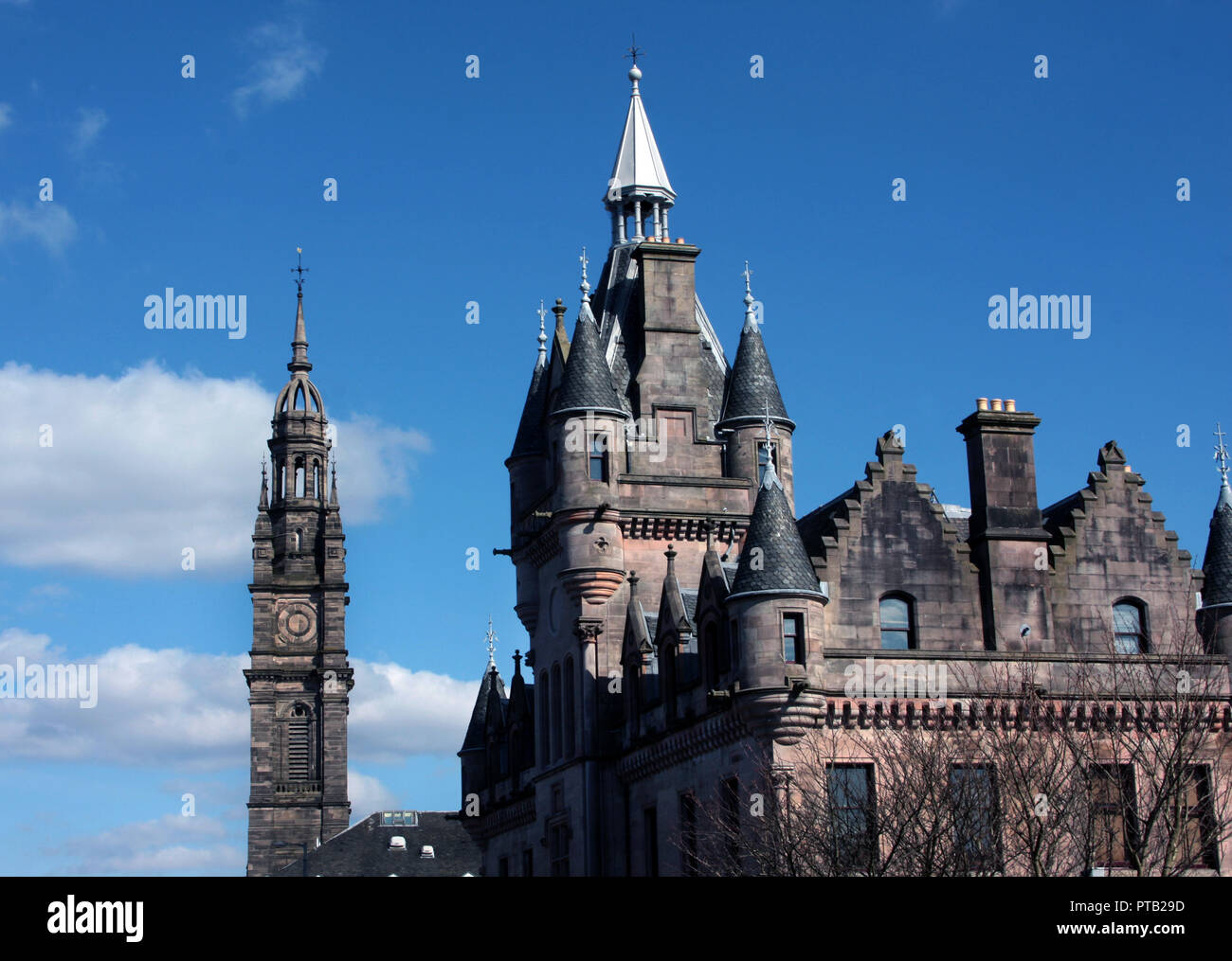 The grand baronial building that is the Sheriff Court in the Scottish town of Greenock looks magnificent against a blue sky with the tower of St George's church just behind it. Stock Photo