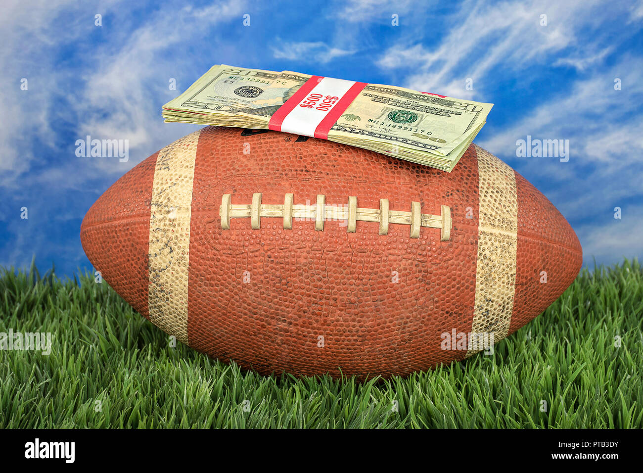 wrapped money stack on American football with sky background on grass Stock Photo