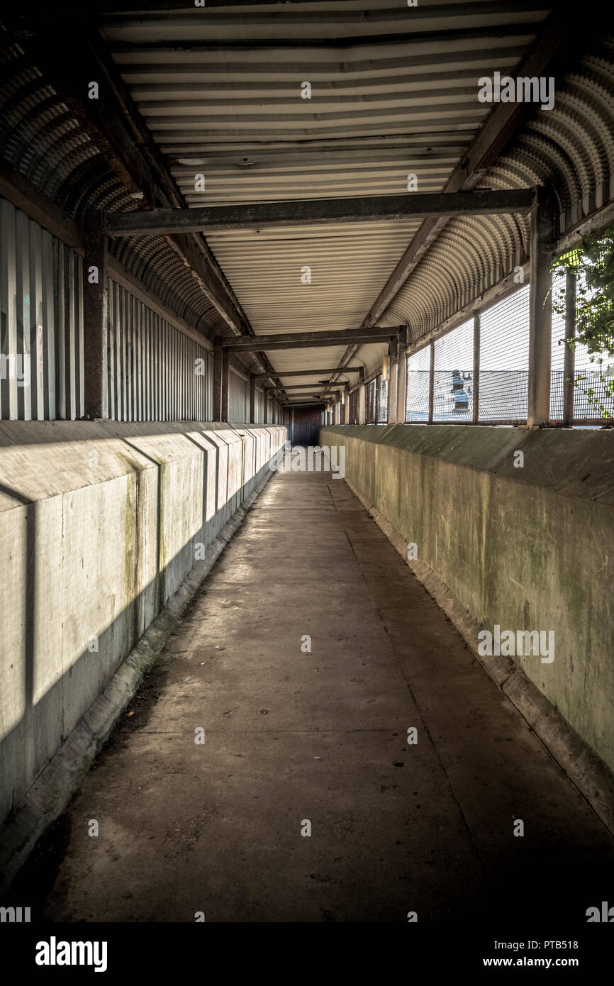 Looking down a covered walkway in an industrial area Stock Photo