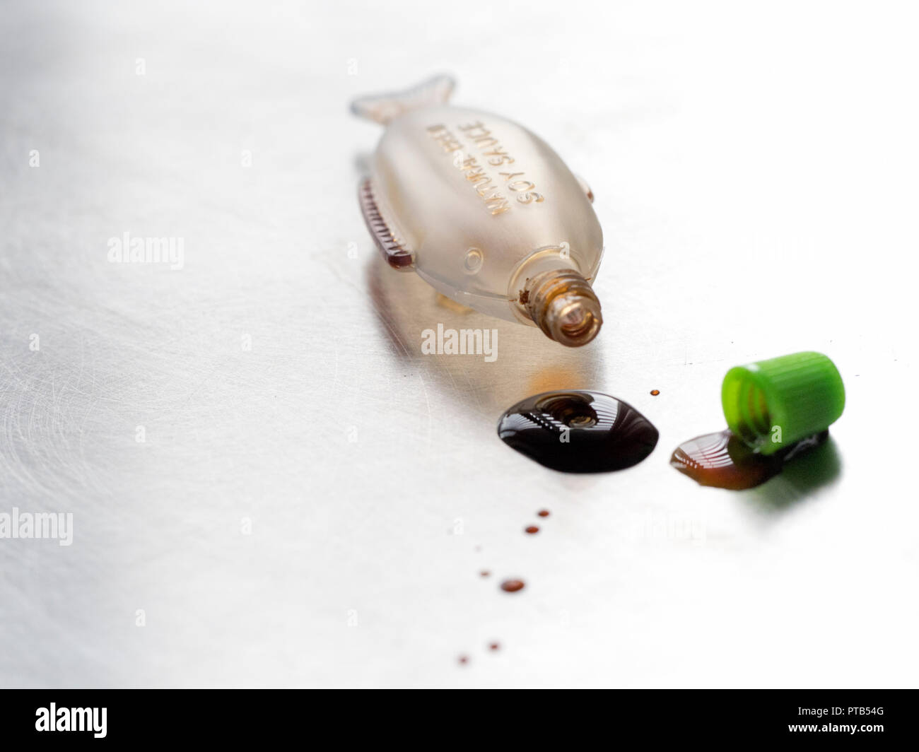 Fish shaped mini Soy sauce bottle spilling drops of sauce Stock Photo