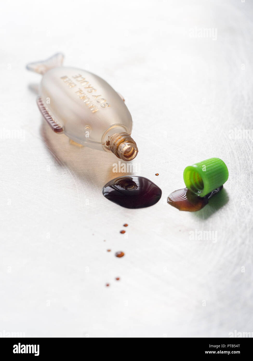 Fish shaped mini Soy sauce bottle spilling drops of sauce Stock Photo