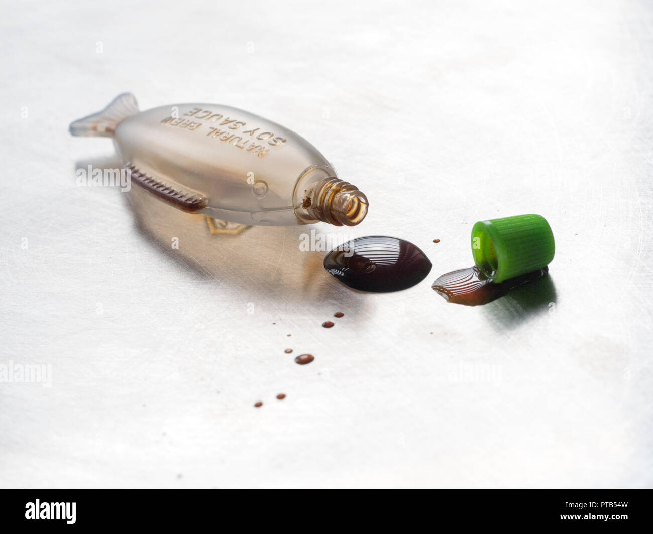 Fish shaped mini Soy sauce bottle spilling drops of sauce Stock Photo