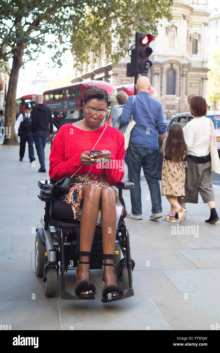 LONDON, UK- SEPTEMBER 14 2018: People on the street during the London Fashion Week. A girl in red mohair sweater and short black leather skirt in whee Stock Photo