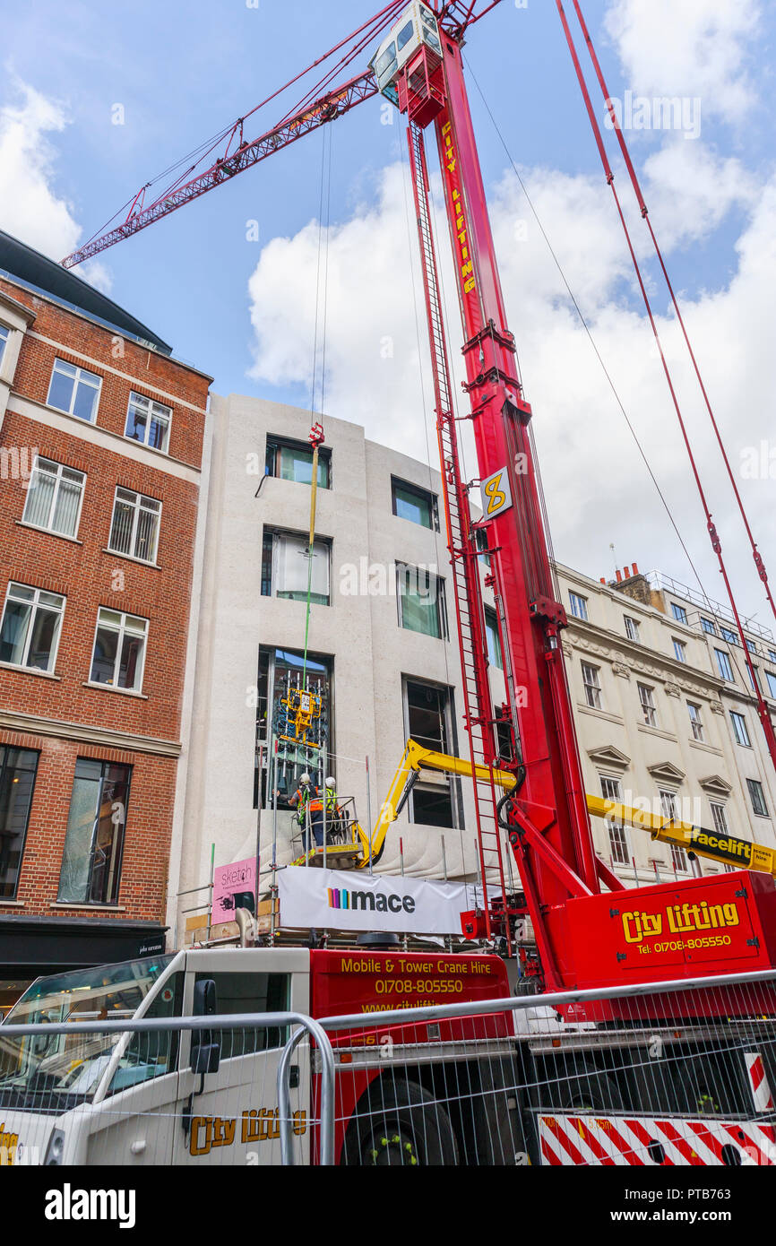Building contractor Mace workers on a cherry picker hoist carefully