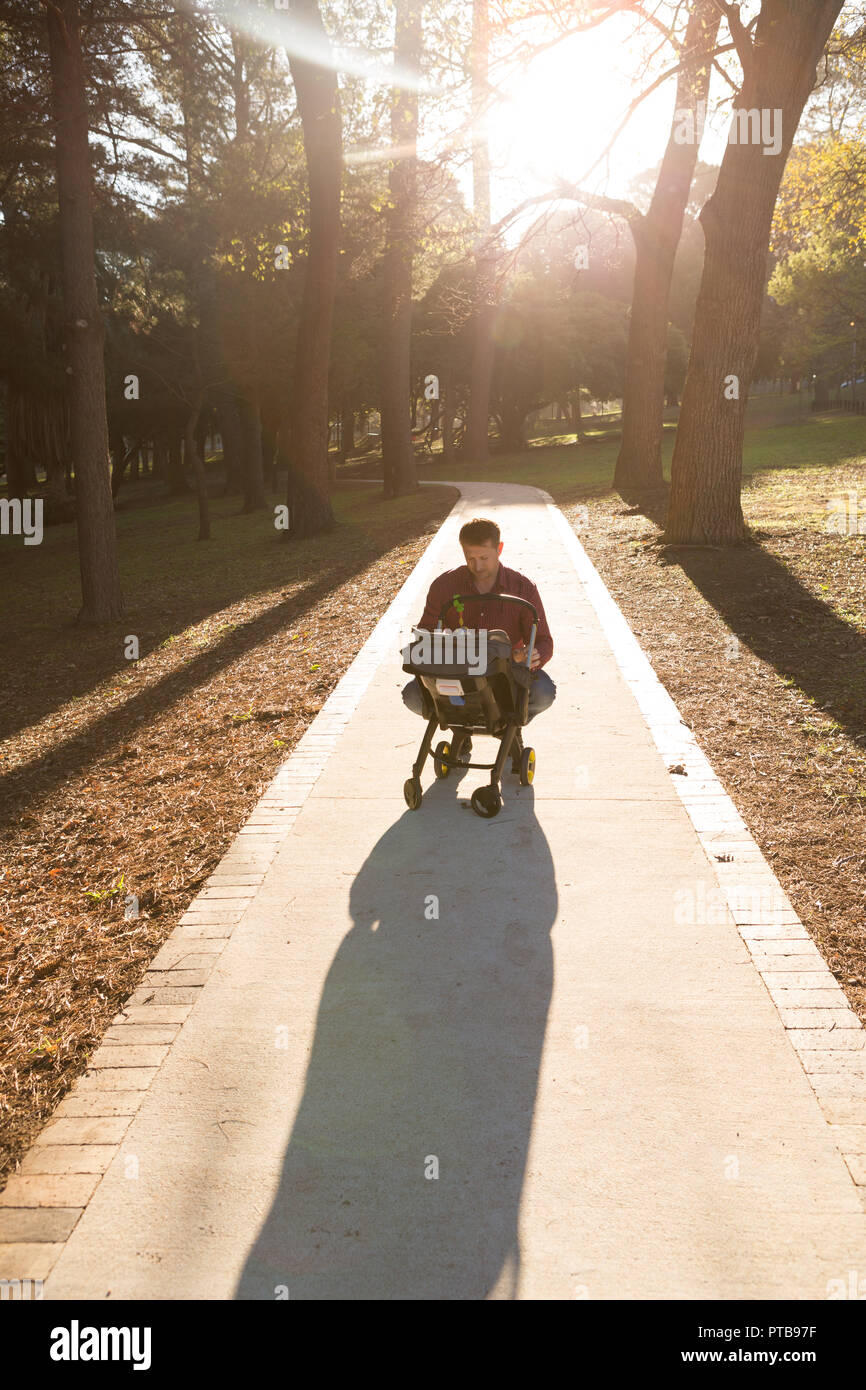 Father with his baby boy in a pram in the park Stock Photo