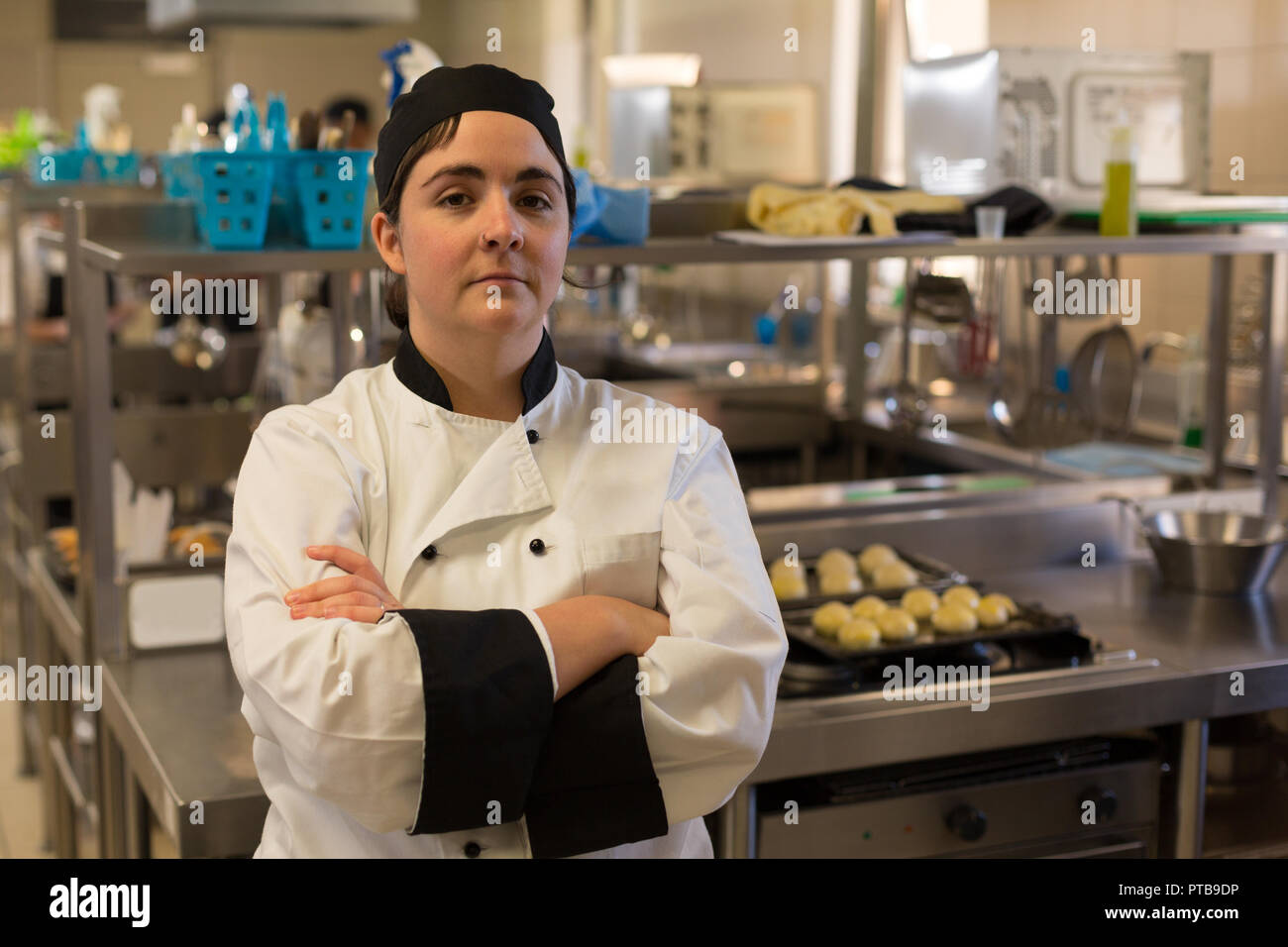 Female chef standing with arms crossed in kitchen Stock Photo