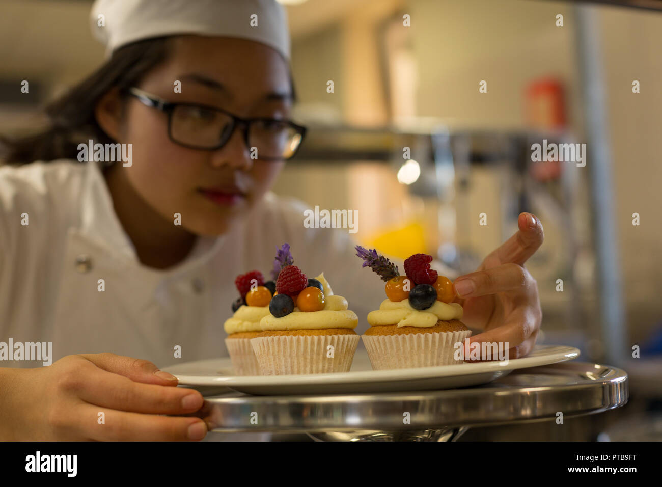 Female chef arranging muffins on a plate Stock Photo