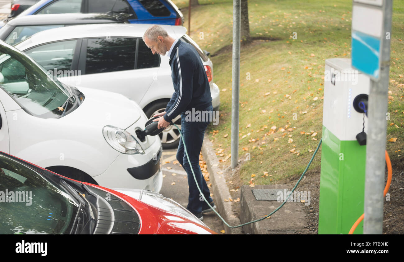 Man charging electric car at charging station Stock Photo