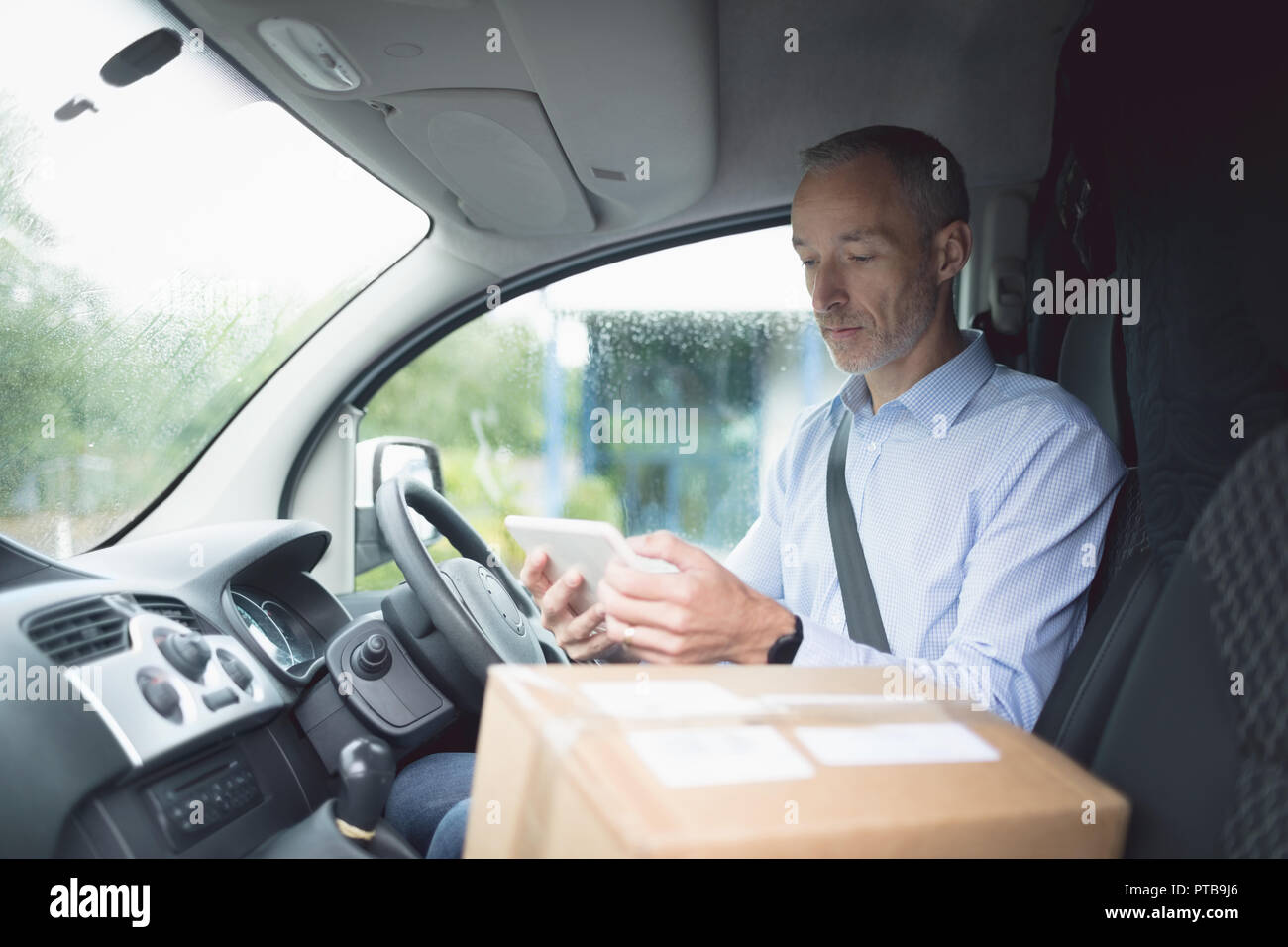 Delivery man using digital tablet in delivery van Stock Photo