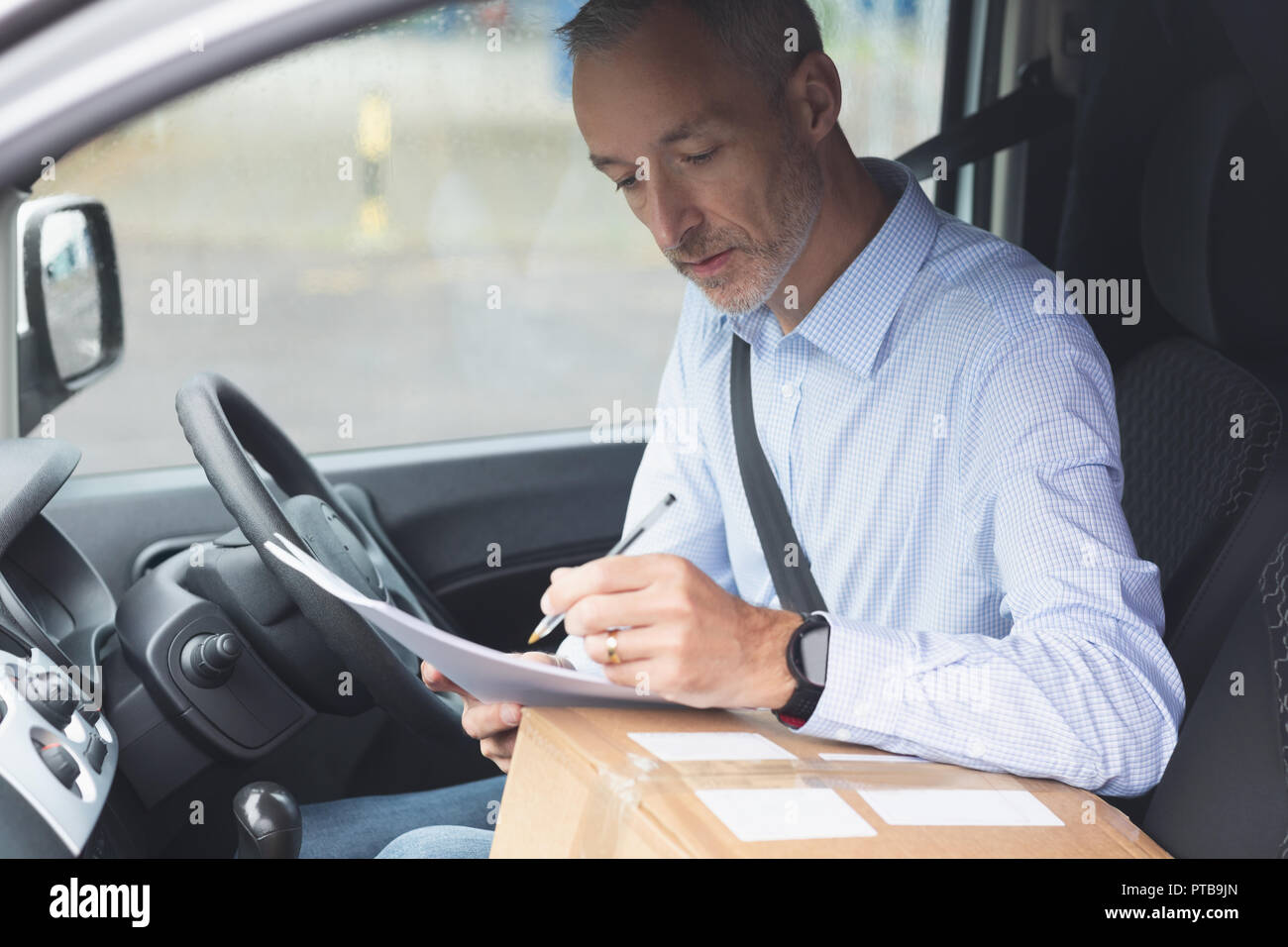 Delivery man writing on paper in delivery van Stock Photo