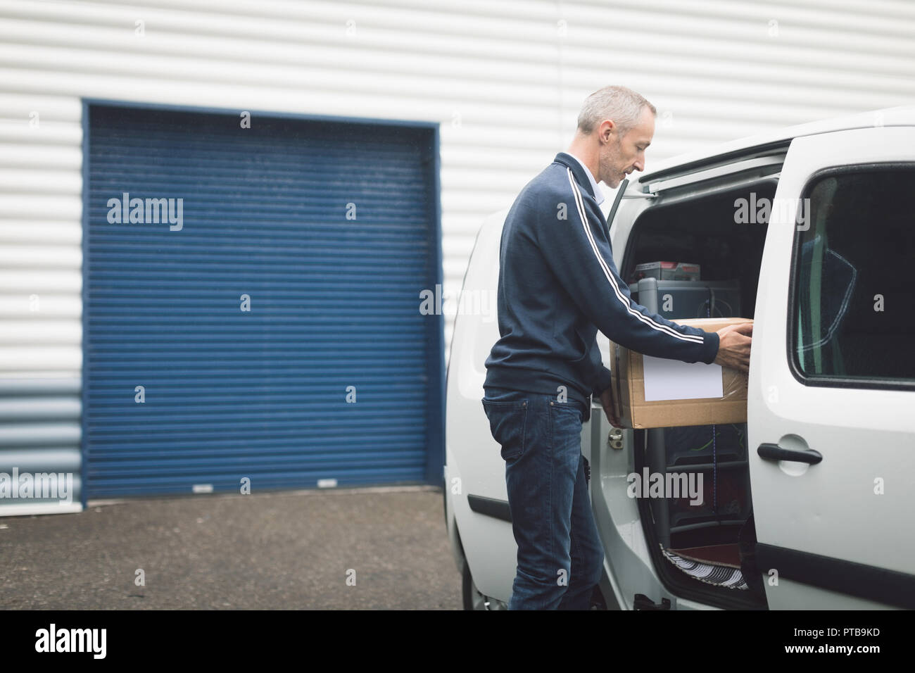 Delivery man unloading parcel from delivery van Stock Photo