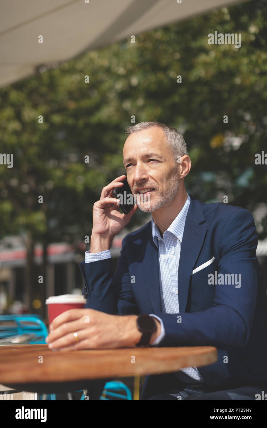 Businessman talking on mobile phone at outdoor cafe Stock Photo