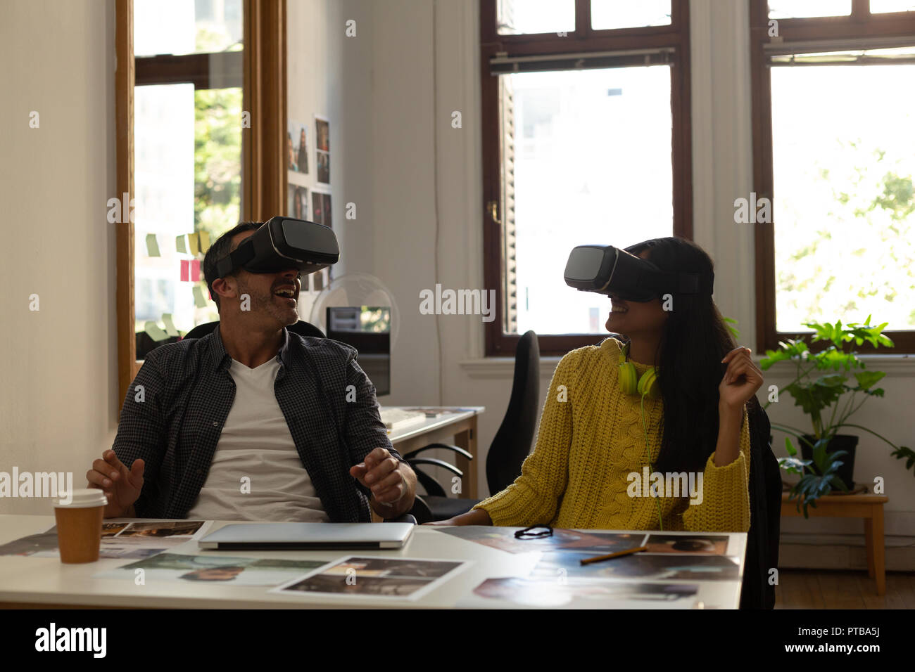 Business colleagues using virtual reality headset on desk Stock Photo