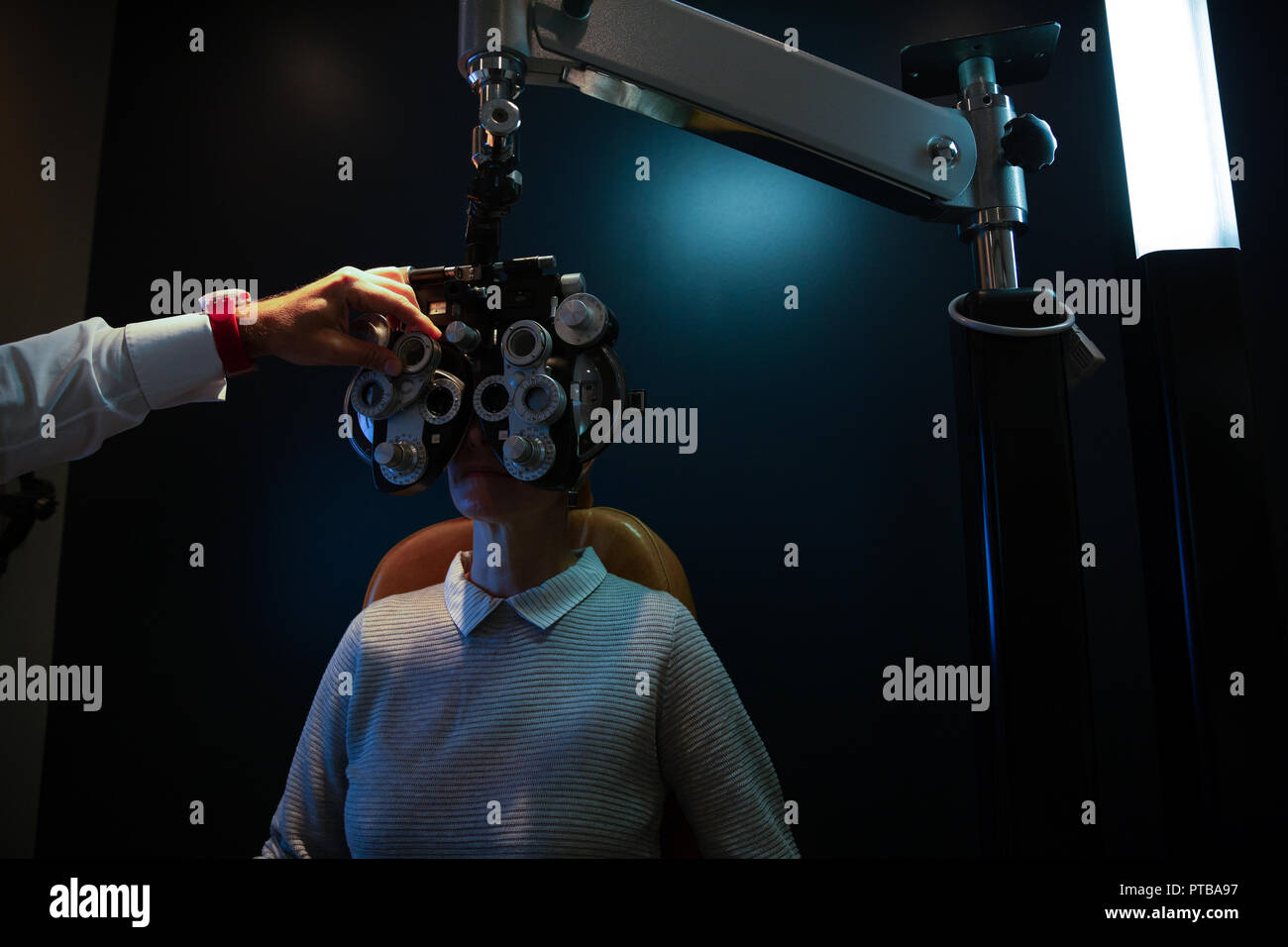 Optometrist examining patient eyes with phoropter Stock Photo