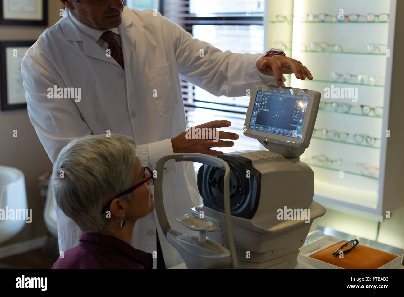 Optometrist explaining eyesight report on autorefractors screen Stock Photo