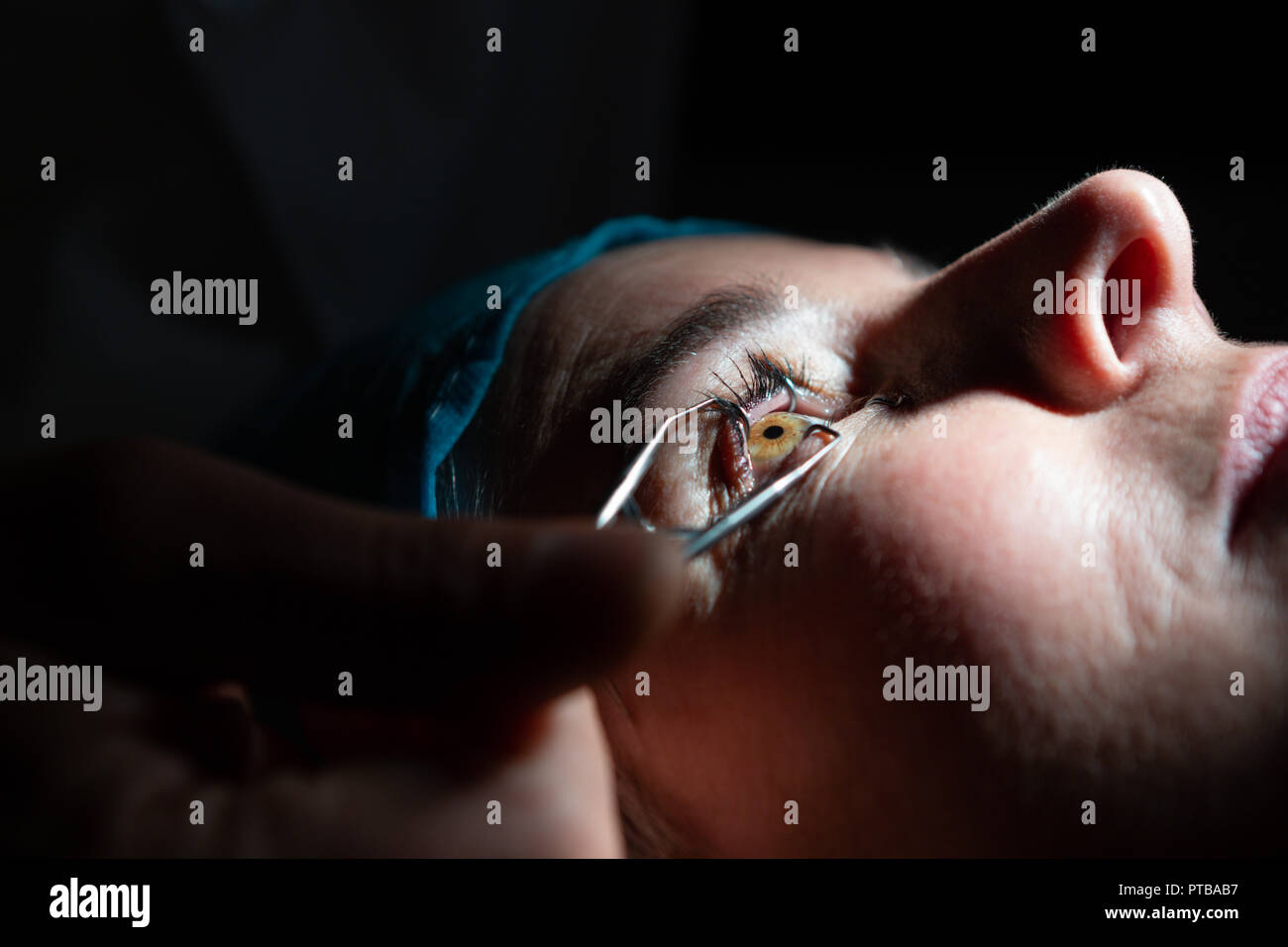 Optometrist examining patient eyes with eye test equipment in clinic Stock Photo