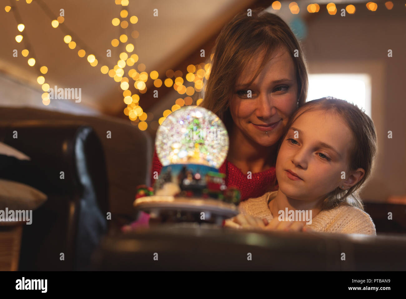Mother and daughter looking at Christmas tree snow globe Stock Photo