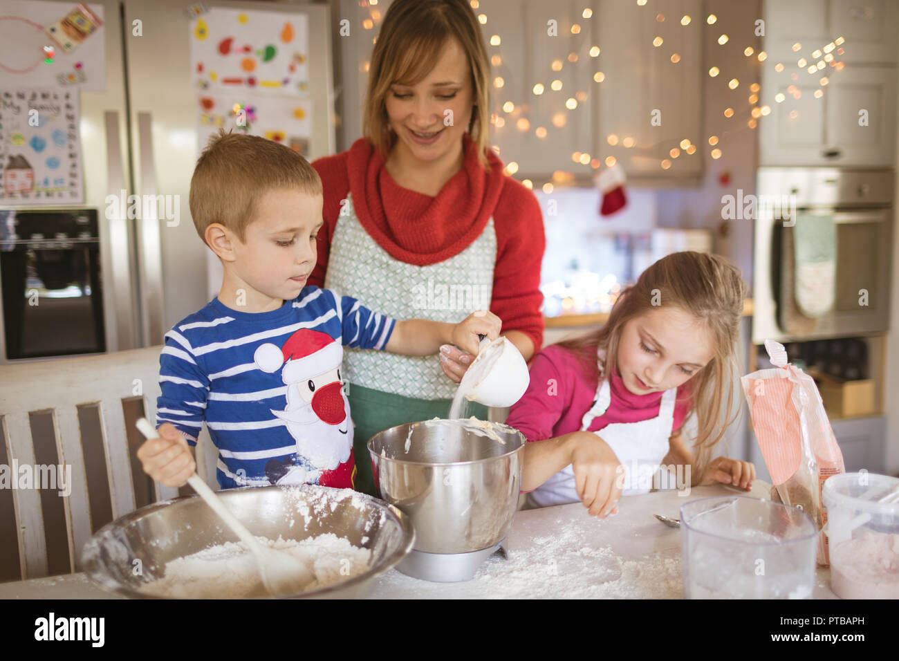 Mother and kids preparing dough to make Christmas cookies Stock Photo