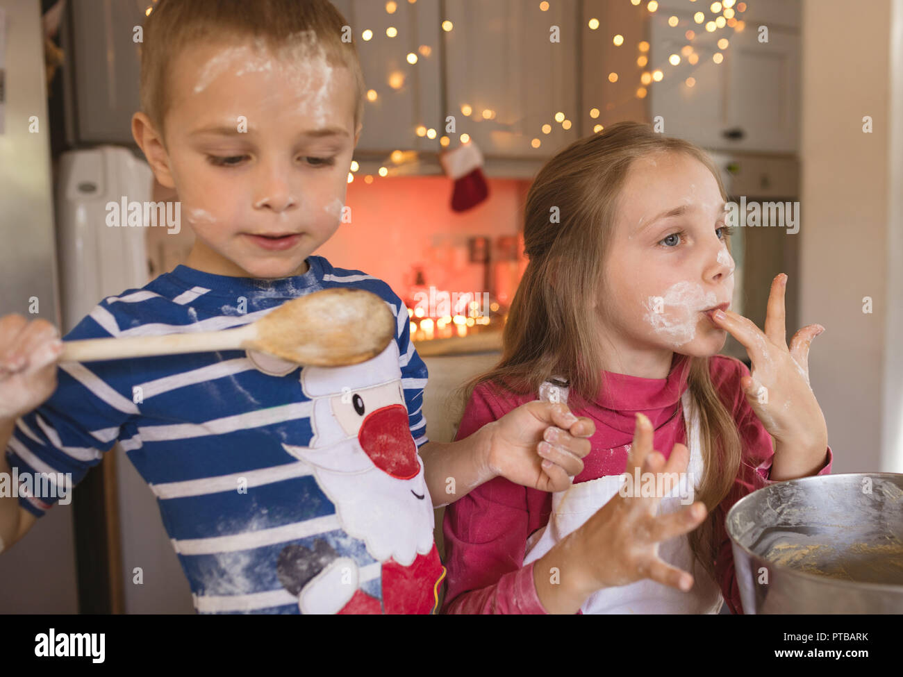 Siblings tasting the cookie batter in the kitchen Stock Photo