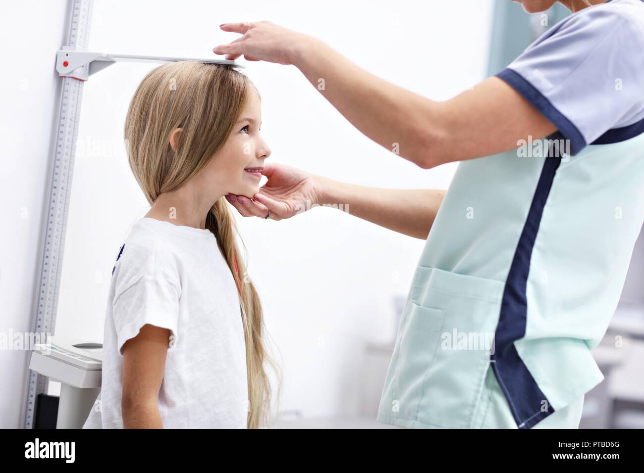 Picture of female doctor measuring height of girl in clinic Stock Photo