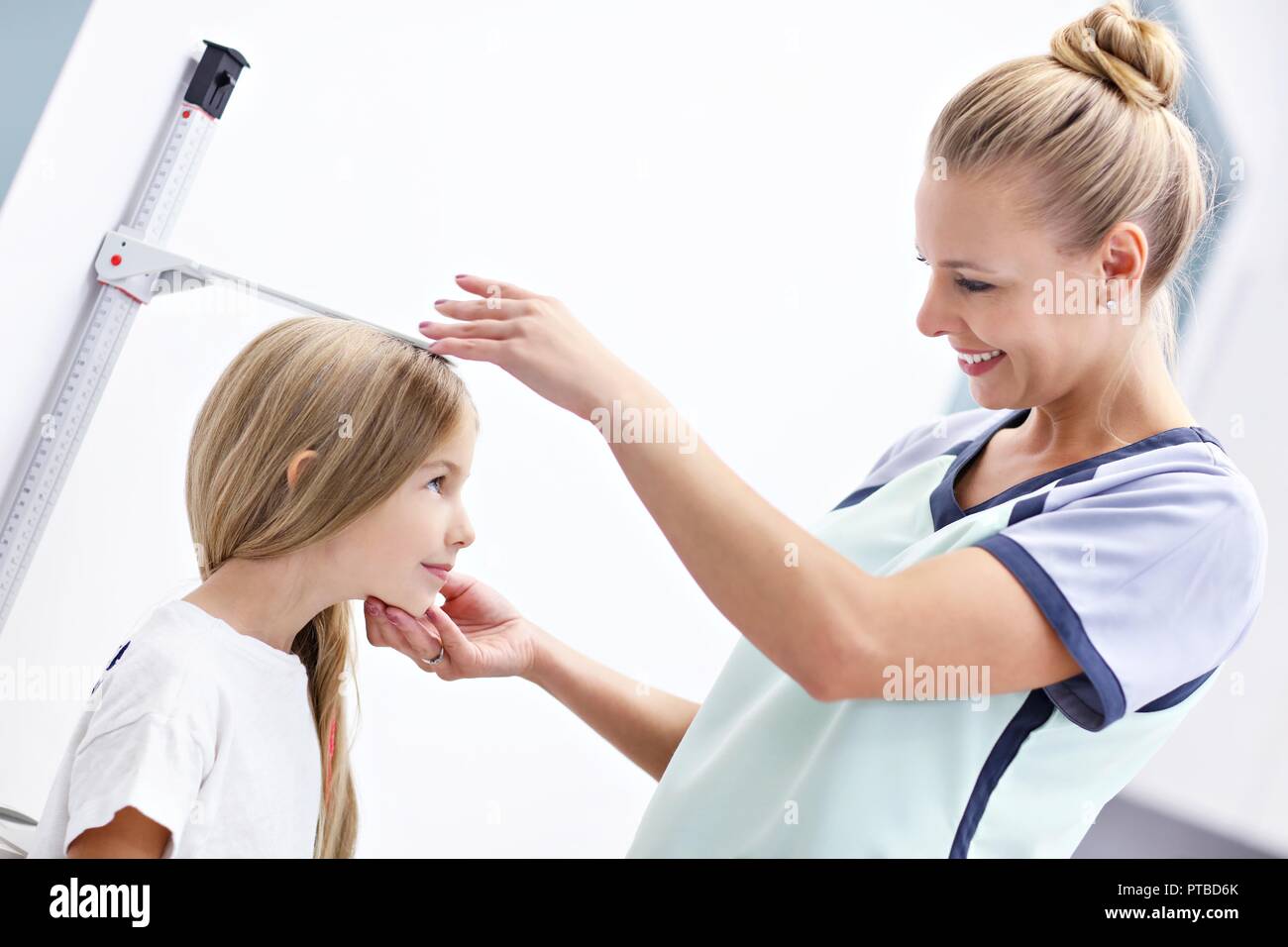 Picture of female doctor measuring height of girl in clinic Stock Photo