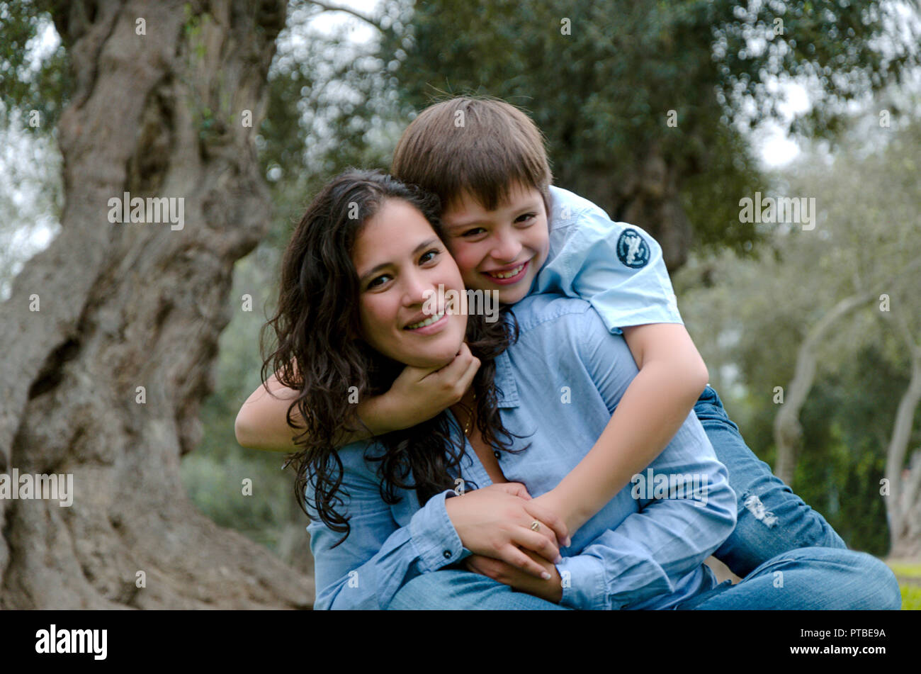 Child hugging his mother smiling on an autumn afternoon in the park ...