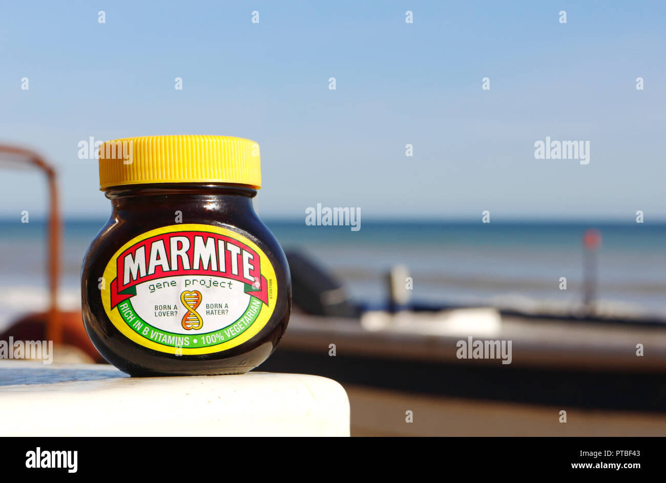 A jar of Marmite set by inshore fishing boats on the North Norfolk coast. Stock Photo