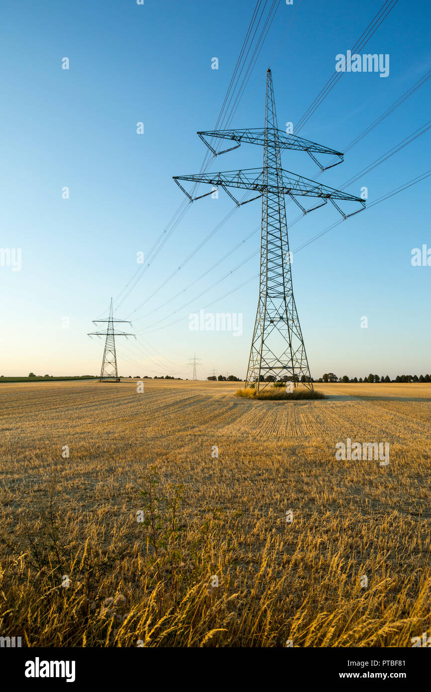 Electricity pylons and power lines on dry agricultural land on an extremely dry summer evening in July 2018, Saxony-Anhalt, Germany Stock Photo