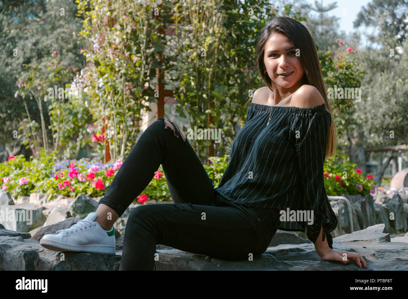 Sport fashion Girl sitting on rock in the green park Stock Photo