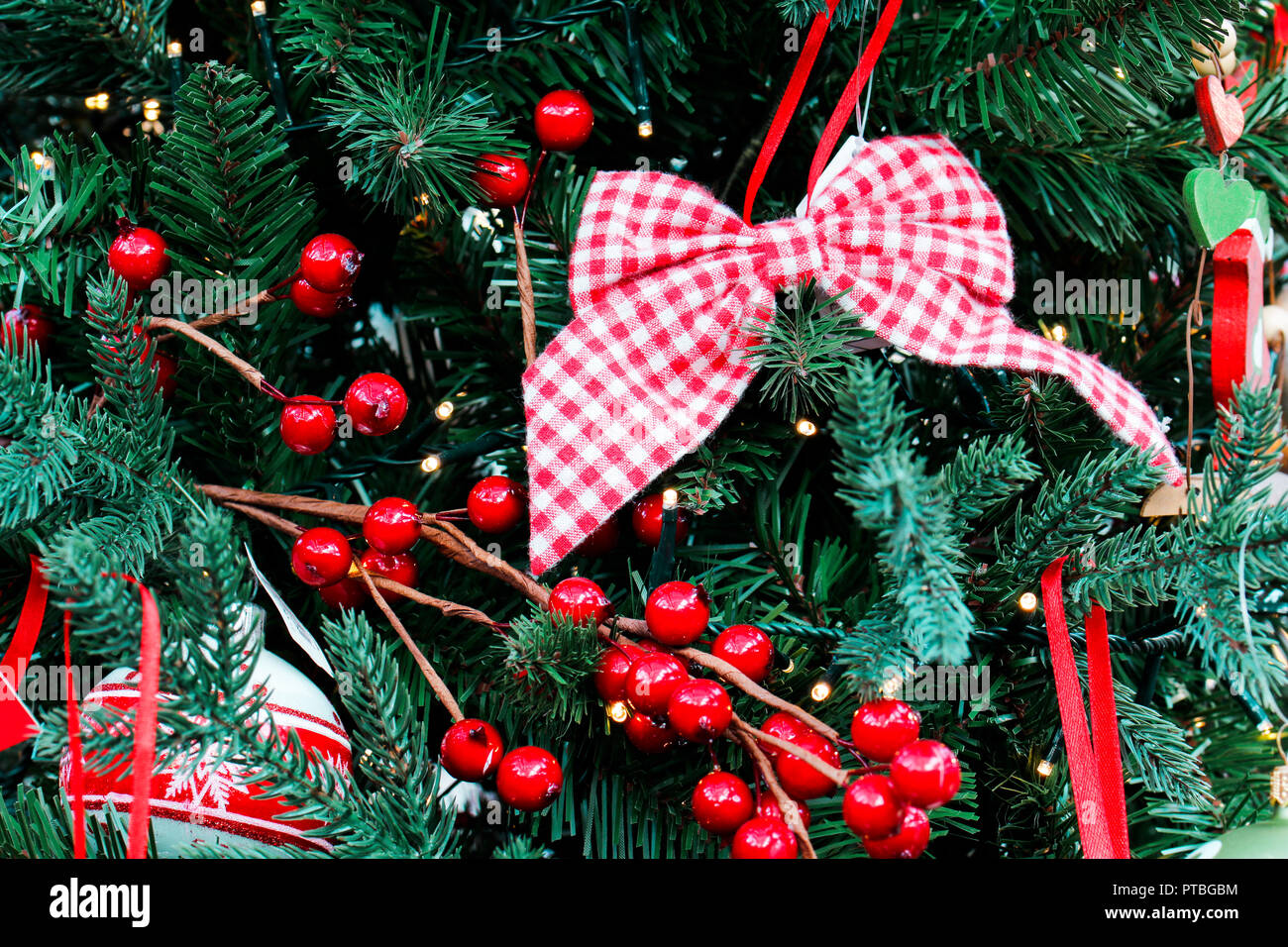 Close up of Christmas tree decorated with bow and red berries Stock Photo