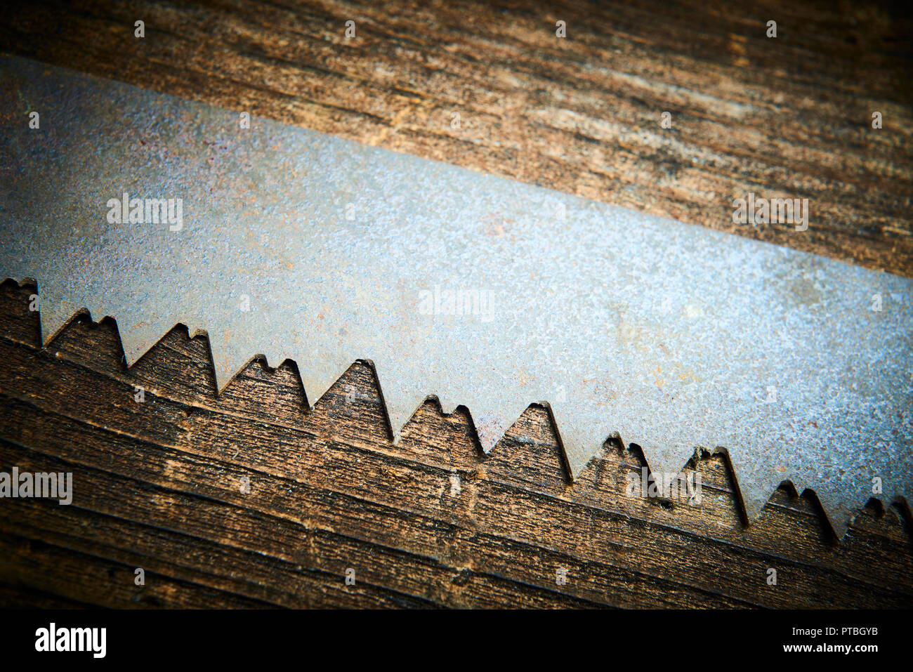 Close up of an old and rusty antique handsaw om wooden desk. Selective focus Stock Photo