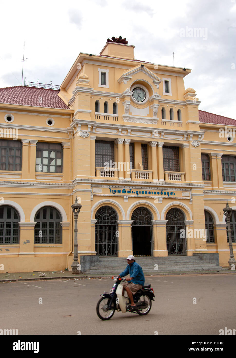 Cambodian man on a motorbike passing in front of the french-era post office, Phnom Penh province, Phnom Penh, Cambodia Stock Photo