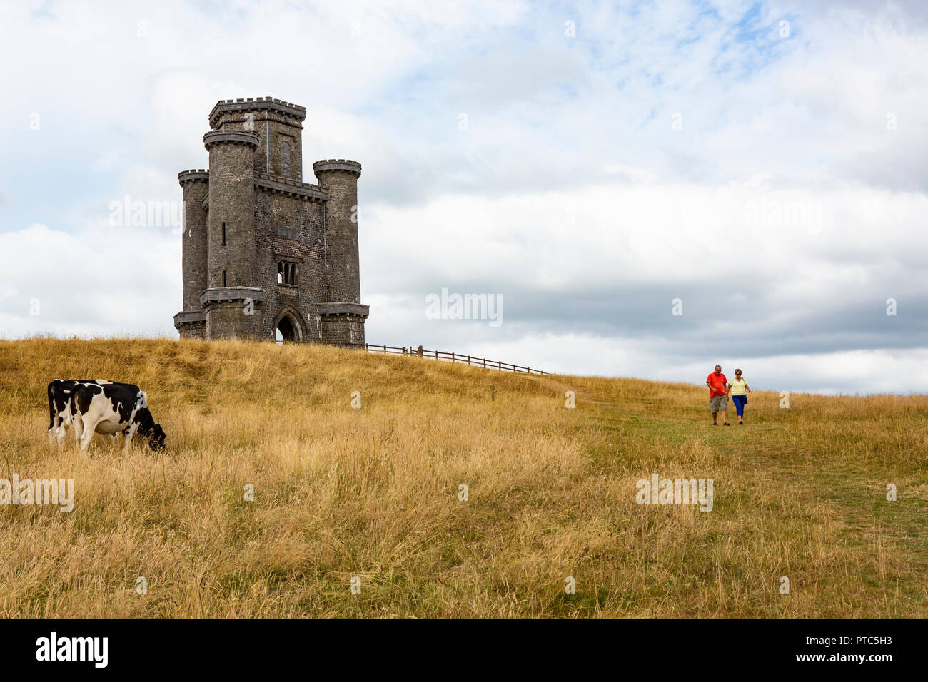 A couple of tourists walk down from Paxton's Tower through a field of cows Stock Photo