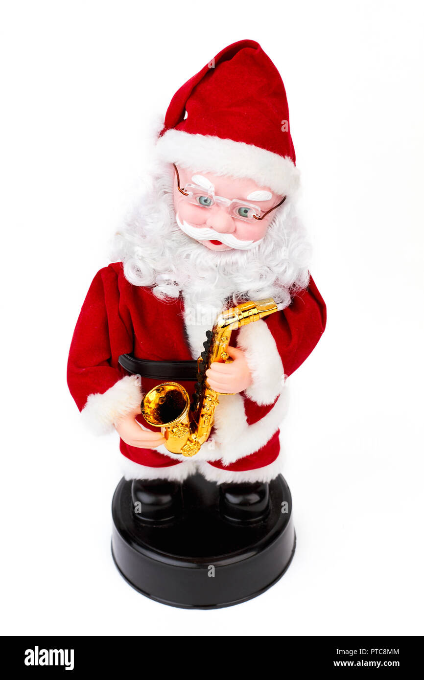 Beautiful Santa Claus toy with saxophone. Cute musical grandfather frost toy with golden saxophone isolated on white background, studio shot. New Year Stock Photo