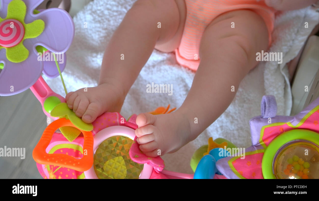 Newborn baby stroller toys. Infant baby legs and colorful rattle toys. Early activity of infants. Stock Photo