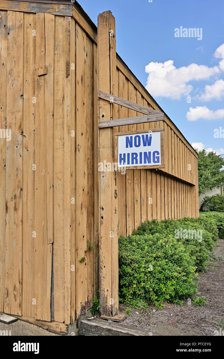 Now hiring sign hanging outside a commercial business indicating workers needed in Montgomery Alabama, USA. Stock Photo