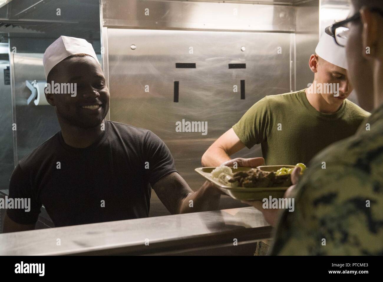 PACIFIC OCEAN (July 10, 2017) Culinary Specialist 2nd Class De’Metric Knowles, a native of San Francisco, assigned to the supply department onboard the amphibious transport dock ship USS San Diego (LPD 22) serves meals on the ship’s mess line. San Diego is embarked on a scheduled deployment as part of the America Amphibious Ready Group, which is comprised of more than 1,800 Sailors and 2,600 Marines assigned to the amphibious assault ship USS America (LHA 6), the amphibious dock landing ship USS Pearl Harbor (LSD 52), and San Diego. Stock Photo