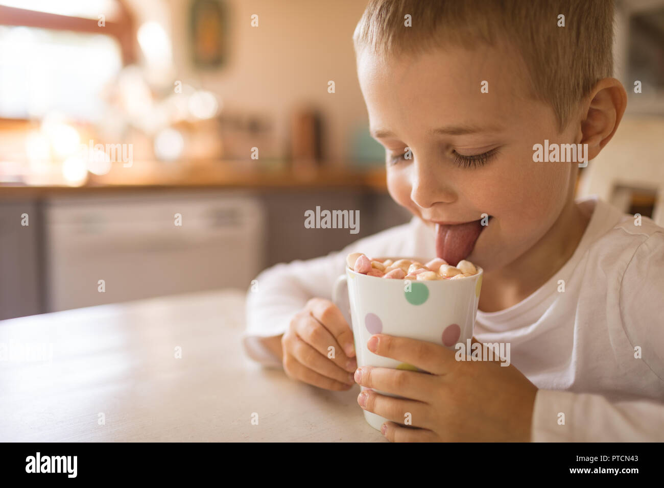 Boy licking a cup full of marshmallows Stock Photo