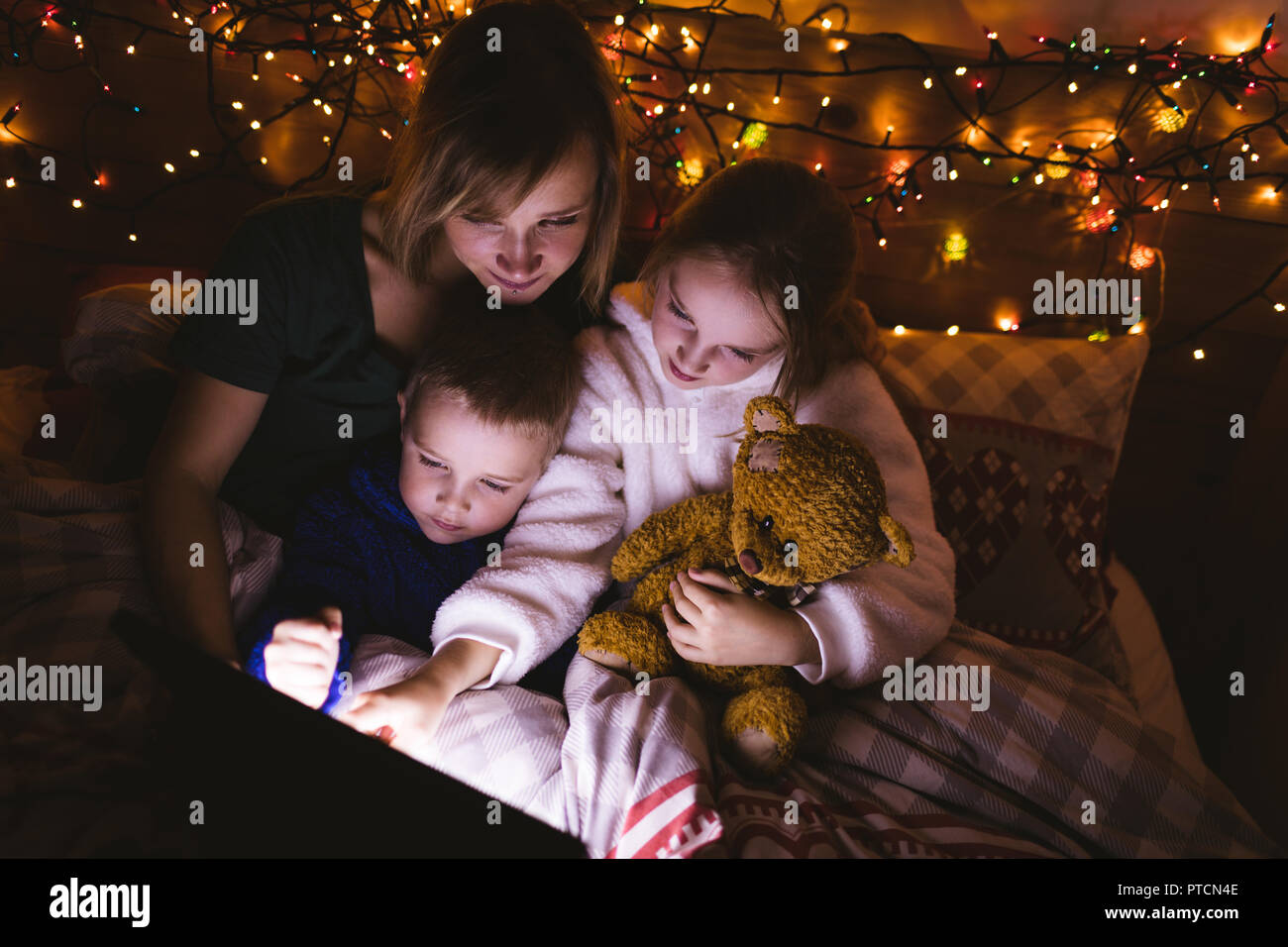 Mother and kids using digital tablet on bed Stock Photo