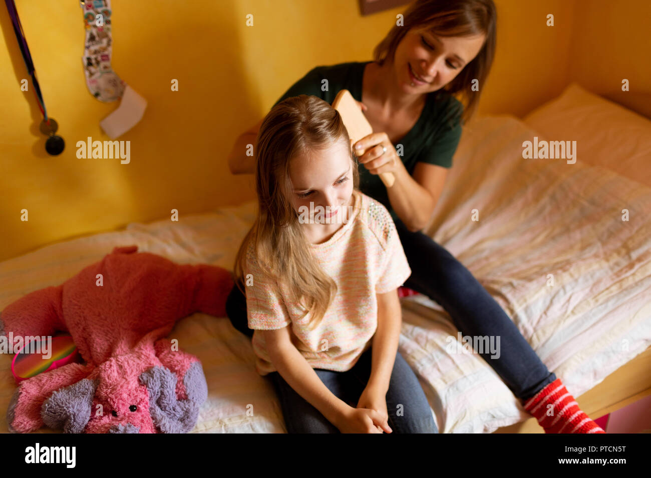 Mother combing daughters hair at home Stock Photo